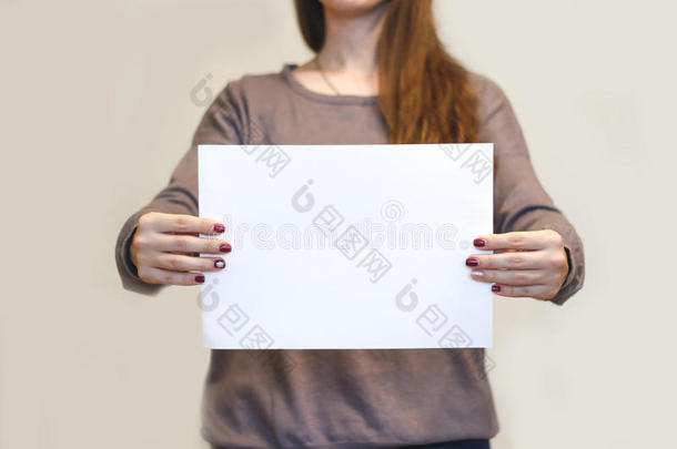 女孩水平地拿着白色的A4空白纸。 小册子介绍。 小册子牵着手。 女人显示清晰的偏移纸。 表格t