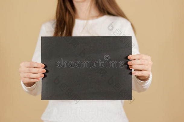 女孩垂直拿着黑色A4空白纸。 小册子介绍。 小册子牵着手。 女人显示清晰的偏移纸。 床单