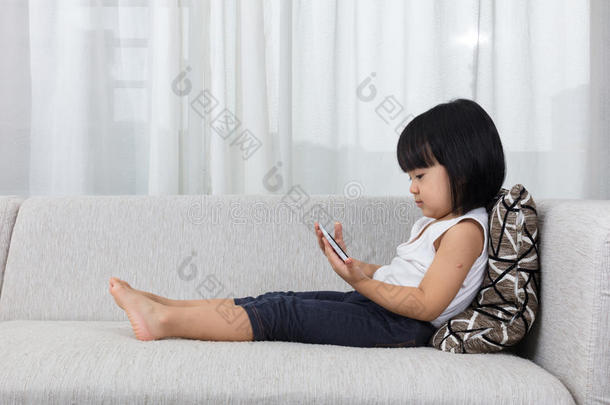 亚洲中国小女孩躺在沙发上拿着电话