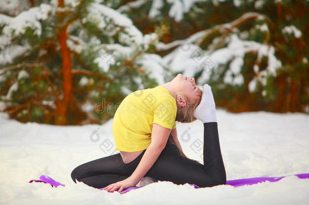 美丽的女人在雪地里户外做瑜伽