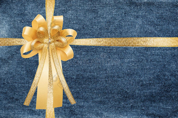 金色丝带和蝴蝶结，包裹在蓝色牛仔牛仔裤纹理礼品盒背景