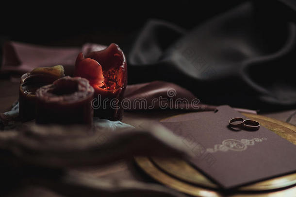 美丽的<strong>婚礼粉</strong>红色和棕色卡片的图形艺术，带有两个戒指的<strong>金色</strong>盘子，蜡烛烟雾，织物，木头上的障碍