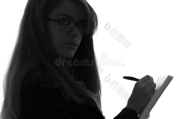一个女人在办公室工作的<strong>黑白剪影</strong>，手里拿着一个文件夹和一支钢笔