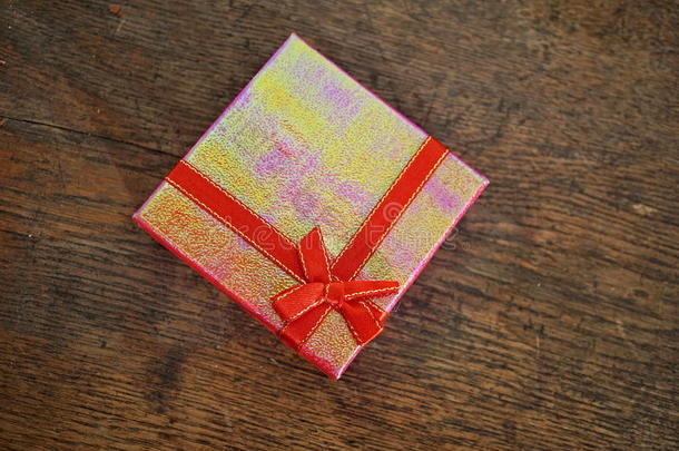 封闭的粉红色<strong>礼品</strong>盒，红色丝带和<strong>金色</strong>缝纫在木制背景上，作为礼物和得到礼物的象征