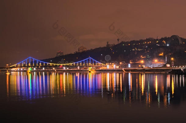 人行桥的美丽照明反射在水中。 沿着第聂伯河的长廊的夜景