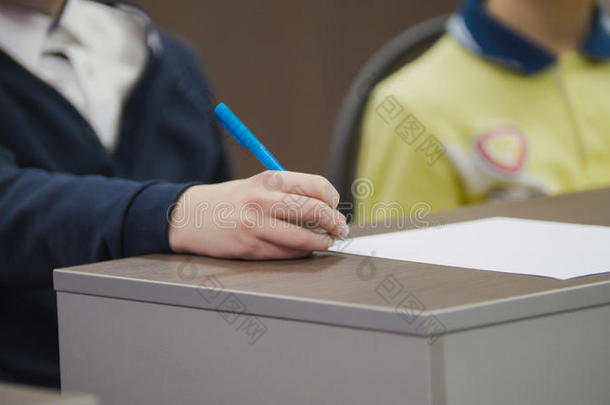 上课期间同学们在学校-孩子们坐在桌子上拿着钢笔