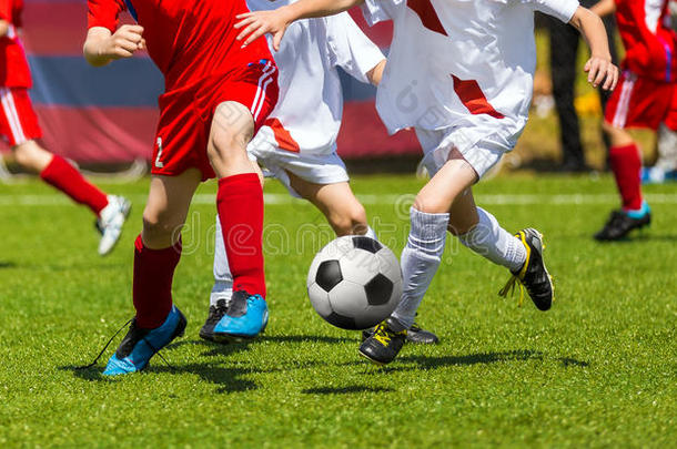 足球踢足球。 足球运动员决斗。 孩子们在运动场上玩足球游戏。 男孩们在绿草地上踢足球比赛