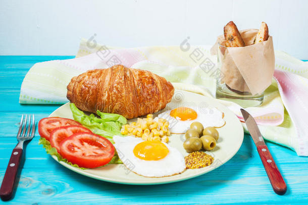 木制桌子上的<strong>早餐</strong>。 <strong>煎鸡蛋</strong>，西红柿，牛角面包