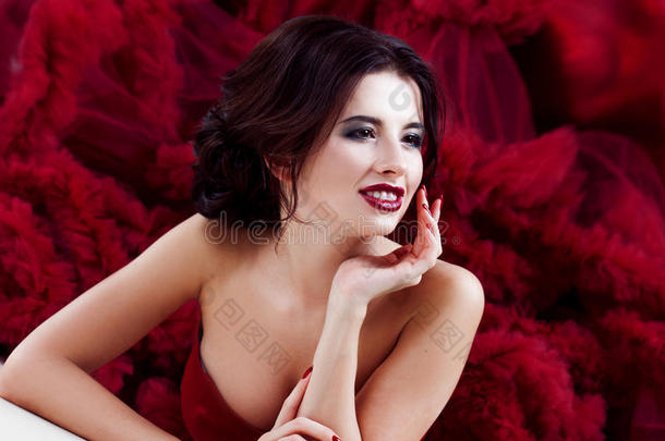 美丽的黑发模特女人穿着晚红礼服。 美丽时尚，豪华化妆和发型