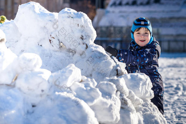 有趣的小男孩穿着五颜六色的衣服，在下雪的时候在户外玩耍。 冬季在寒冷的雪达上与孩子们积极休闲