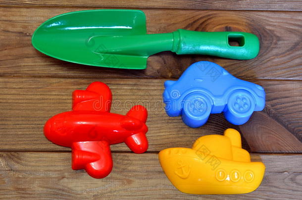 孩子们`棕色木制背景上的海滩玩具。 绿色<strong>塑料</strong>铲子，红色<strong>塑料</strong>飞机，黄色<strong>塑料</strong>船，蓝色<strong>塑料</strong>车
