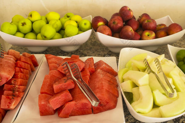 切新鲜西瓜和甜瓜。 桌子上的新鲜水果，红苹果和绿苹果，橘子。