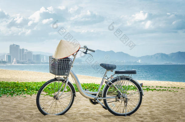 自行车停在海滩沙滩上。 在车把上挂越南帽子。 越南