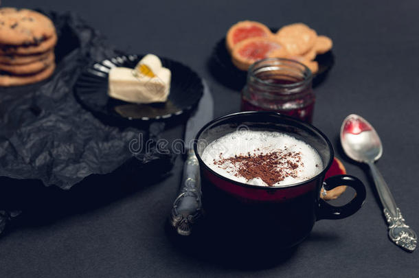 一杯咖啡，卡布奇诺，黑色桌子背景上有巧克力饼干和饼干。 下午休息时间。 早餐。