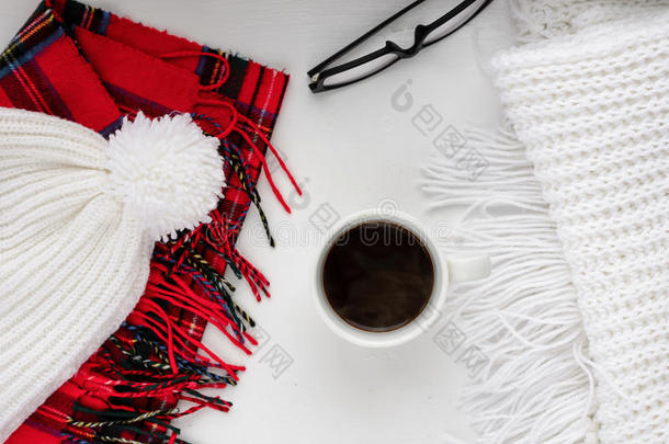 手工编织羊毛围巾和帽子。 冬天的衣服。 木制背景上的热咖啡杯。 概念舒适的气氛与一个进去。 t