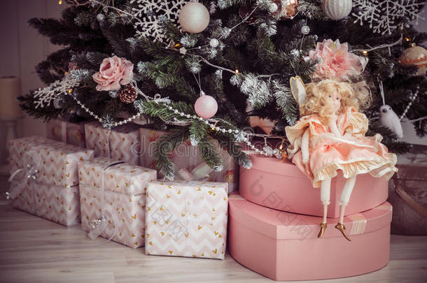 圣诞礼物和树下的洋娃娃。粉色装饰。