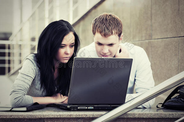 年轻的商务情侣在户外使用笔记本电脑