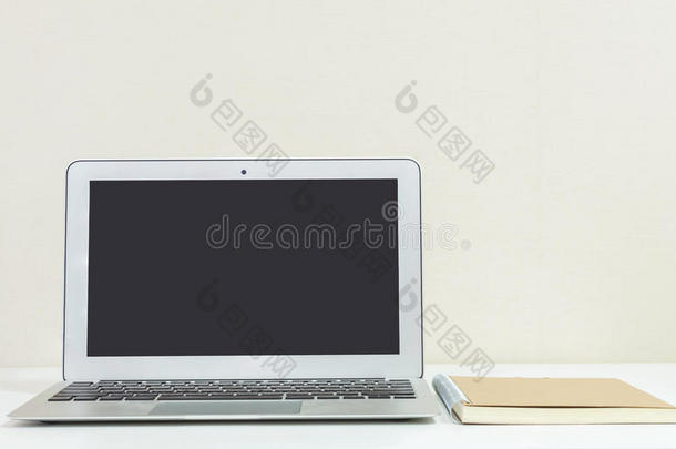 特写电脑笔记本上模糊的白色木桌和奶油色壁纸墙在房间纹理背景，美丽的工作pl