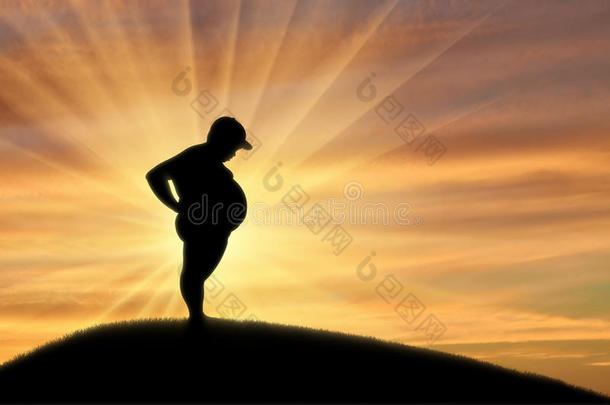 胖孩子站在日落的背景上