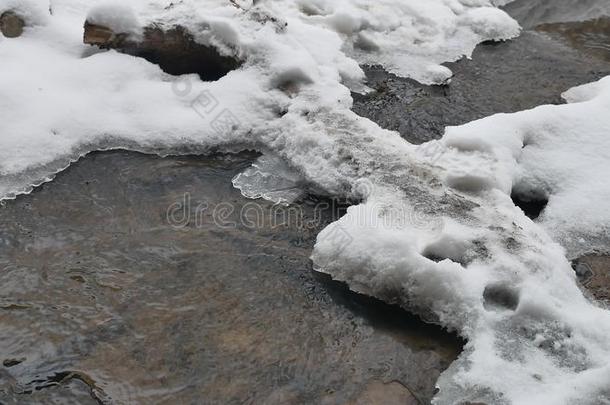 小溪在树林里冬天流水，一条小河在雪地上自然景观