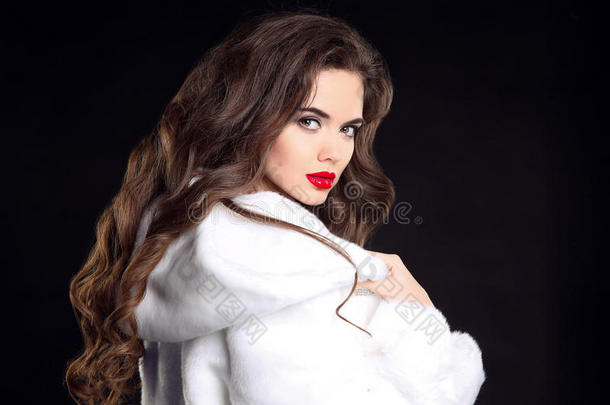 穿着白色毛皮大衣的漂亮时尚黑发女人肖像。 迷人的女孩模特用红唇化妆，长卷发摆姿势