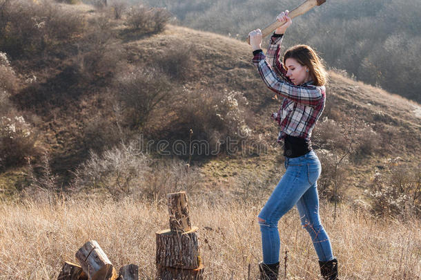 美丽微笑的女人用斧头砍木头