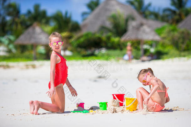 暑假期间可爱的小女孩。 孩子们在白色海滩上玩海滩玩具