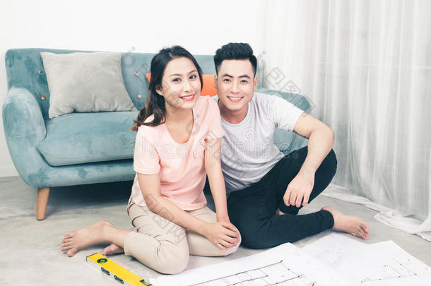 一对年轻漂亮的亚洲成年夫妇正在<strong>看房</strong>子的设计图。