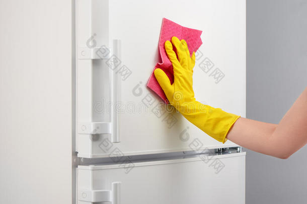 用黄色手套用粉红色抹布清洁白色冰箱