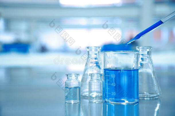 蓝色滴入装有烧瓶和科学实验室的玻璃烧杯中