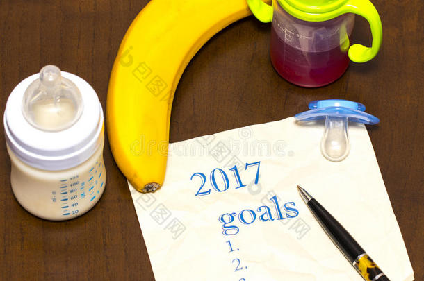 在一张纸上列出了2017年的目标清单，桌上有<strong>一个</strong>奶<strong>嘴</strong>和<strong>一个</strong>婴儿瓶