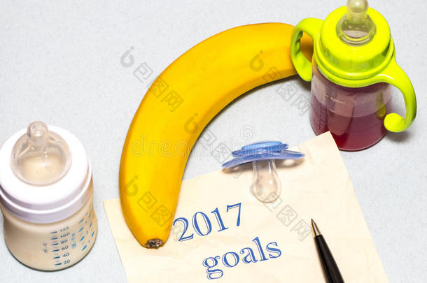 在一张纸上列出2017年的目标清单，上面有一个奶嘴和一个蓝色背景的婴儿瓶