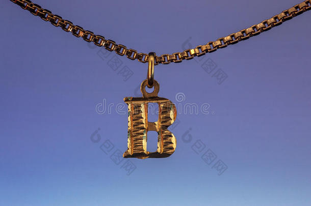 金色b字母吊坠挂在蓝色背景上的金色项链链上