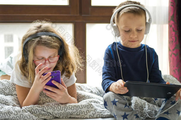 孩子们在床上玩平板电脑和手机