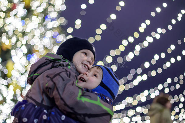 家庭，童年，季节和人的概念-在雪城背景下穿着冬天的衣服快乐