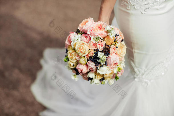 美丽的温柔的婚礼花束玫瑰和定制的鲜花在手