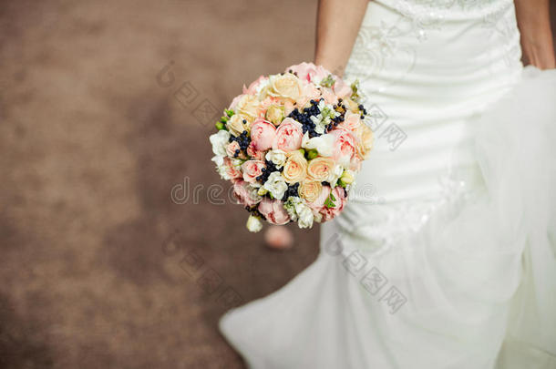 美丽的温柔的婚礼花束玫瑰和定制的鲜花在手