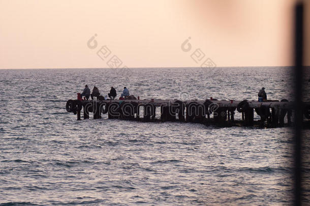 渔民坐在码头上，日落时捕鱼