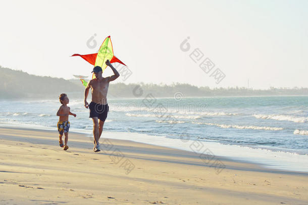 父亲带着儿子，日落在海边玩风筝，幸福的家庭