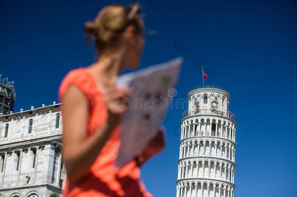 美丽的女游客带着地图欣赏比萨斜塔