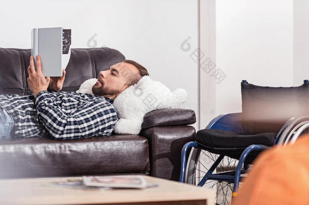 集中迷人的男人在沙发上看书
