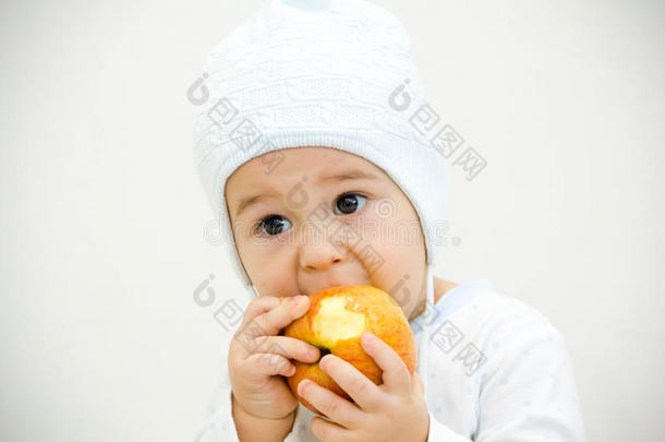 可爱的小白种人男孩11个月大，坐着吃白色背景的红苹果