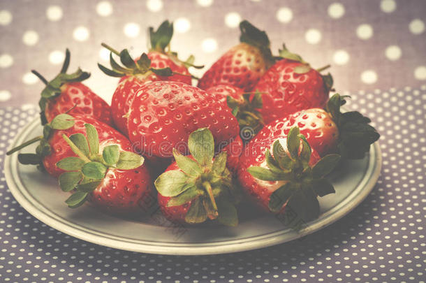 盘子上的新鲜红色成熟草莓。 粉红色虚线背景。