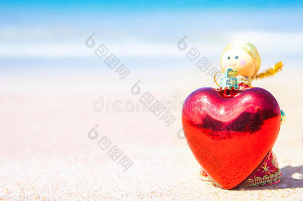 圣诞娃娃一个天使在沙滩上给了一颗心，蓝色