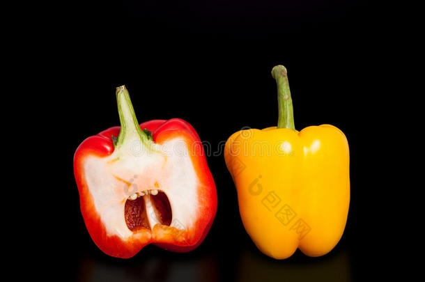 <strong>纯黑色</strong>背景上的一半胡椒。 黄色和红色的辣椒切成两半。