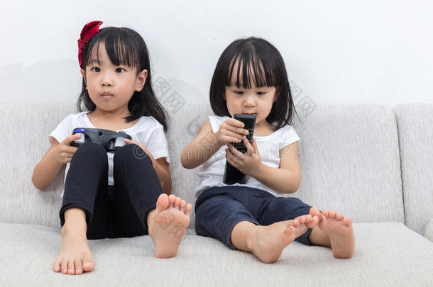亚洲的中国小姐妹在沙发上玩电视游戏