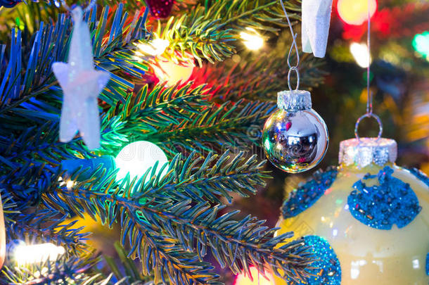 圣诞树装饰品。黄色，有光泽的表面，有蓝色圆圈的球体，发光，周围有明亮的五彩灯光。