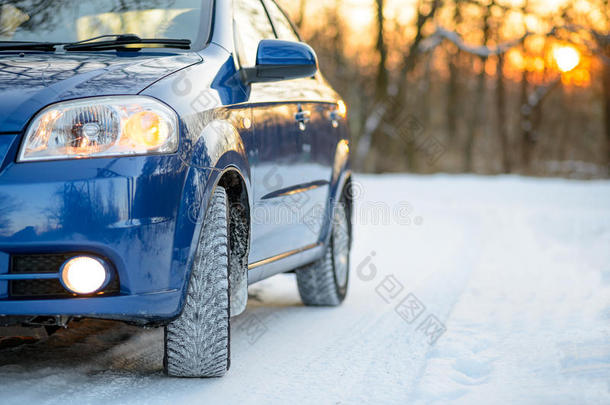 雪路上有冬天轮胎的蓝色汽车。 开车安全。