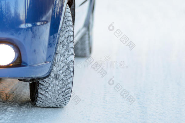 雪路上有冬天轮胎的蓝色汽车。 开车安全。