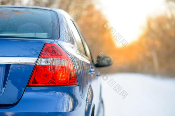 日落时，冬天雪路上的蓝色汽车。 关闭后视镜。 旅行和<strong>驾驶安全</strong>概念。